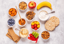 Help Your Kids Make Healthy Snack Choices A marble tabletop with a selection of fruits, vegetables, nuts, crackers, and dips.