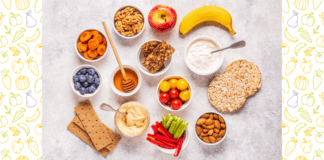 Help Your Kids Make Healthy Snack Choices A marble tabletop with a selection of fruits, vegetables, nuts, crackers, and dips.