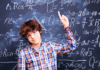How to Help Your Child Love Math A boy stands in front of a blackboard pointing at math equations, suggesting he is learning to love math.