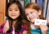 Sight Words that Every 1st Grader Should Know Two girls smiling and holding a card that says "WE"