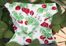 Make These Cute Reusable Sandwich Wraps A homemade reusable sandwhich wrap in a white fabric with a pattern of strawberry plants.