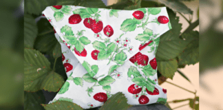 Make These Cute Reusable Sandwich Wraps A homemade reusable sandwhich wrap in a white fabric with a pattern of strawberry plants.