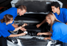 Car Maintenance Tips to Teach Your Teen One adult and four teens stand around a vehicle in blue t-shirts. The adult is teaching car maintenance to teens.