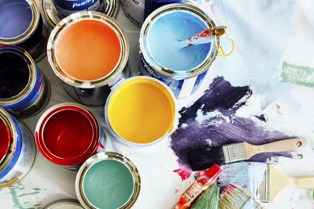 Ariel closeup of five paint cans, one each of light blue, orange, red, yellow, and teal.