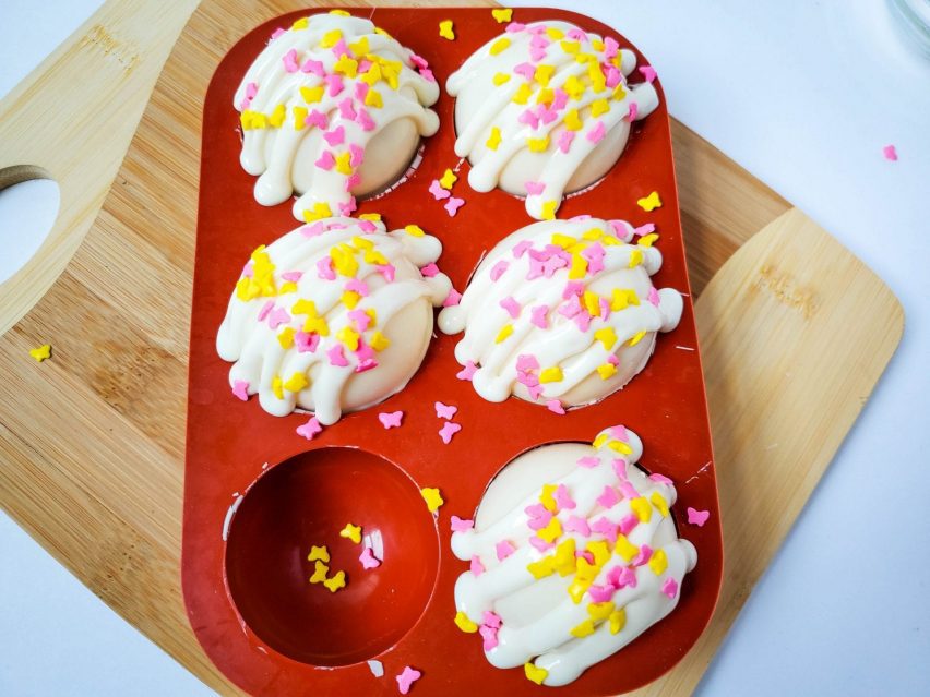 Five white chocolate cocoa bath bombs with butterfly sprinkles on top.