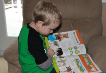 9 Tips For Homeschooling Your Child with Autism A young boy in a green and black sweater is sitting sideways on a chair and looking at a book